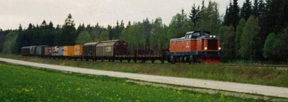 Ett T43-lok drar ett godståg från Ronneby till Karlskrona, runt 1988. I lasterna följer täckta vagnar med pappersrullar från Cascades Djupafors i Kallinge. Vid denna tidpunkt hade företaget ett eget industrispår. Dessutom syns vagnar med 20-fots containrar med mattor från Tarkett i Ronneby, ASG lösflak lastade med mattor samt containervagnar av typ Lgjs med vägvältar från Dynapac i Karlskrona, som vid denna tidpunkt lastades i Ronneby. Foto: Gerrit Söderberg